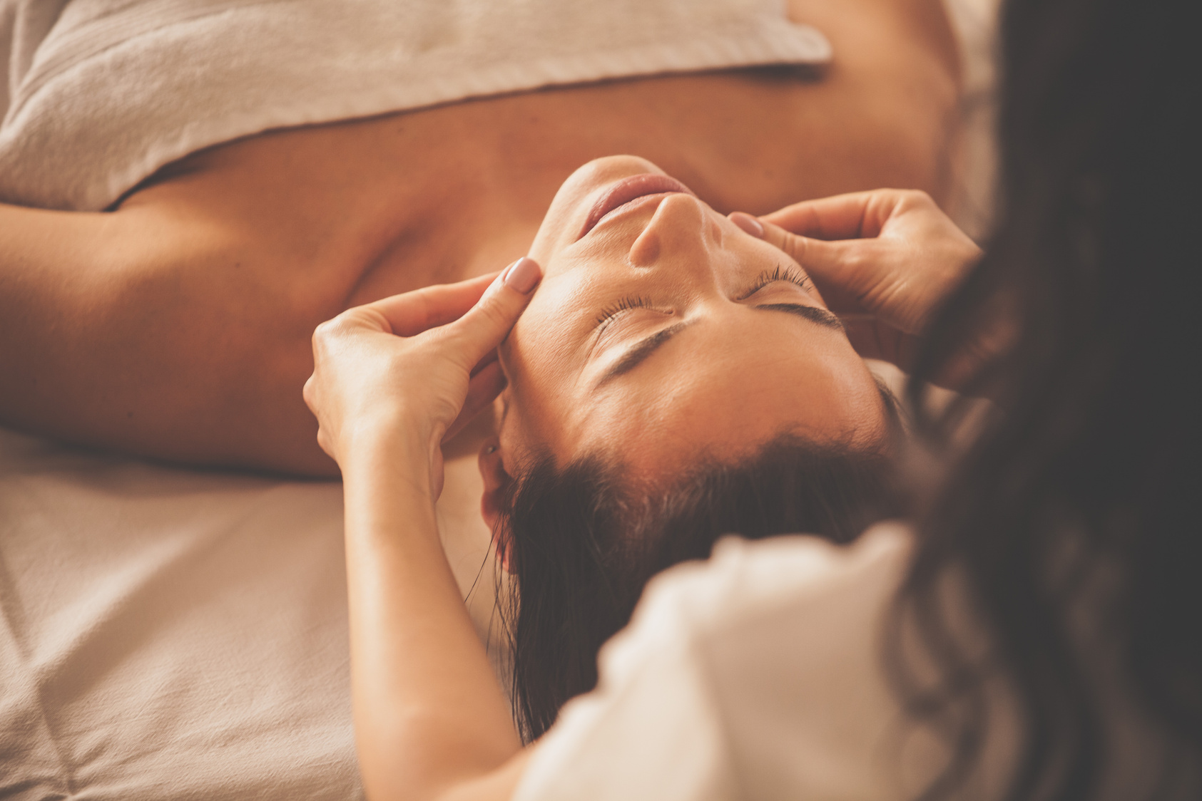 Woman enjoying facial massage at spa